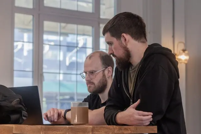 Two male team members working and looking at a laptop screen